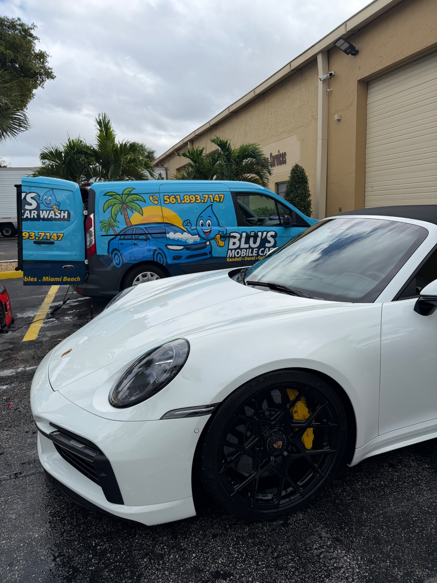 White Porsche 911 Cabriolet next to BLU'S van