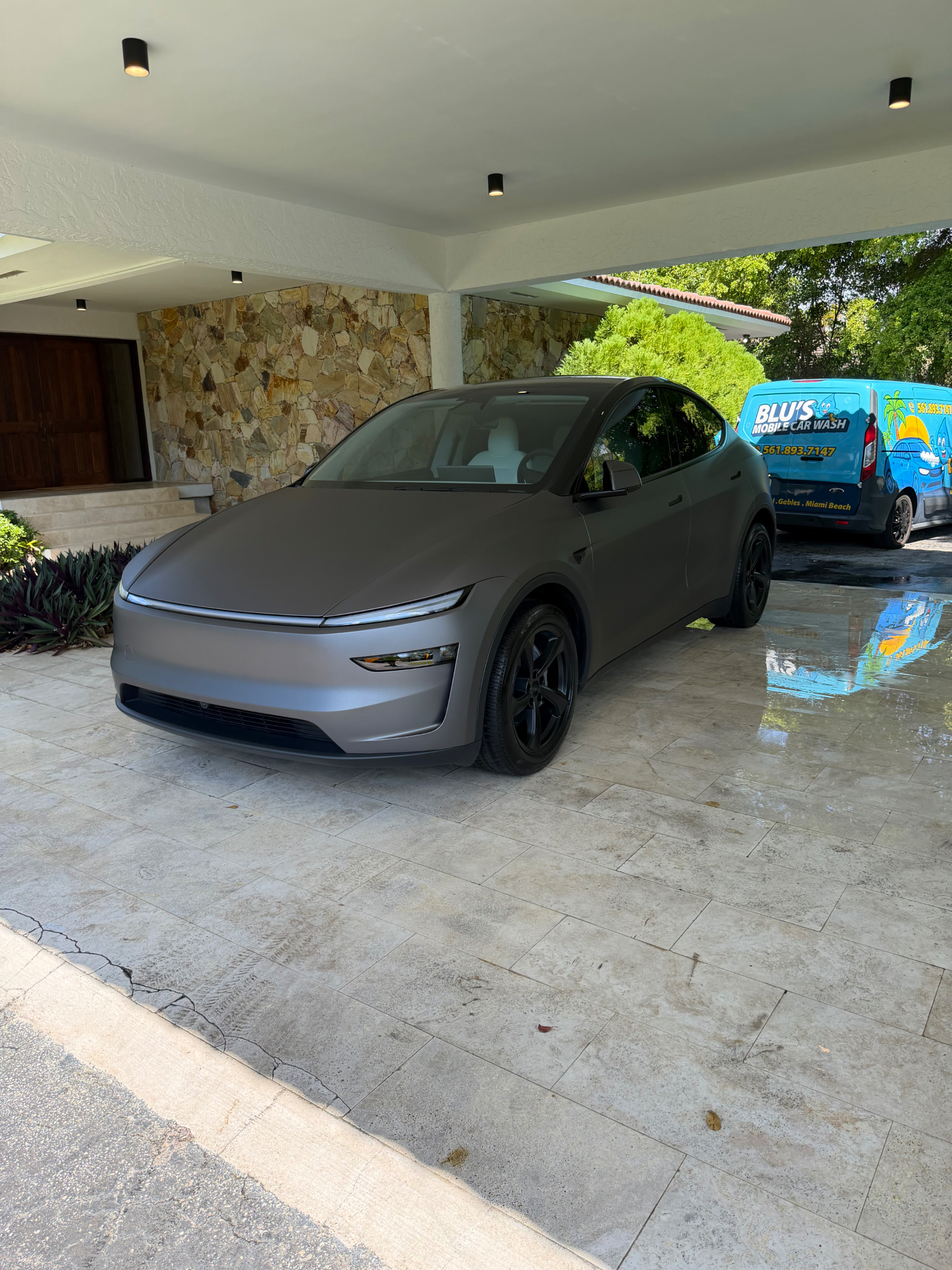 Matte silver Tesla Model Y detailed next to BLU'S van